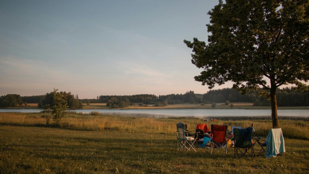 Peaceful lakeside campsite in Treffelstein, Germany with folding chairs under a tree.